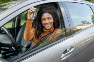 New car owner. Happy woman showing car key.